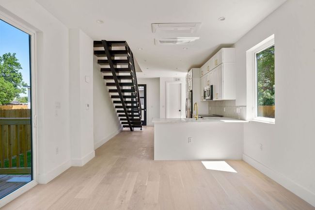 Kitchen featuring stainless steel appliances, white cabinets, light wood-type flooring, and light countertops | Image 12