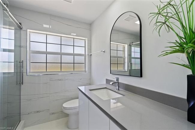 Bathroom with a marble finish shower, visible vents, toilet, and vanity | Image 12
