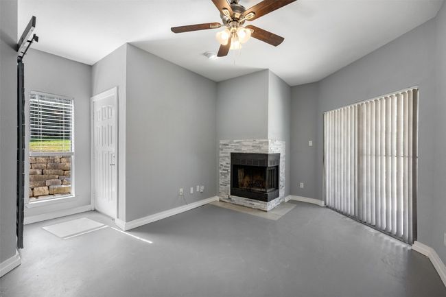Living room with concrete floors, a fireplace, baseboards, and a ceiling fan | Image 5
