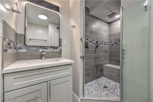 Bathroom with visible vents, a shower stall, vanity, and decorative backsplash | Image 23