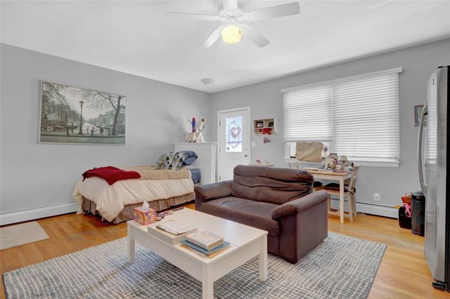Bedroom with light hardwood / wood-style floors, ceiling fan, a baseboard heating unit, and stainless steel fridge | Image 19