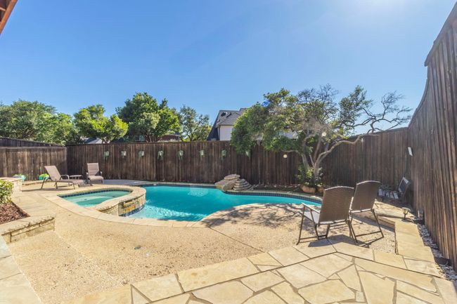 View of swimming pool featuring a fenced backyard, a patio area, and a pool with connected hot tub | Image 32