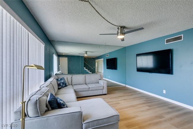 Living area with ceiling fan, light wood finished floors, and a textured ceiling | Image 4