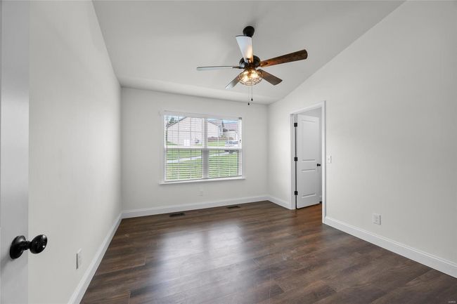 Unfurnished room featuring ceiling fan, dark wood finished floors, baseboards, lofted ceiling, and visible vents | Image 12