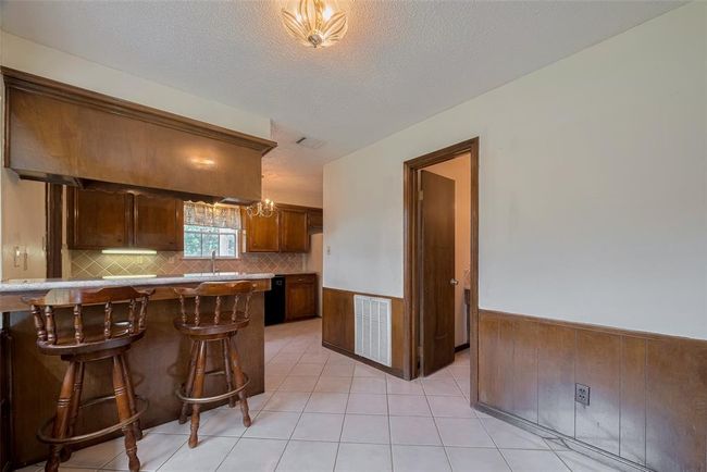 Cozy kitchen with convenient counter seating, perfect for casual dining. | Image 8