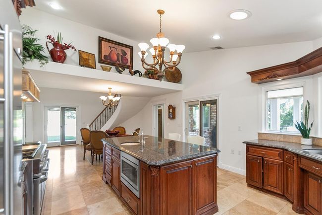Shelf to display your collectables. A second Pella slider is at the other end of kitchen, taking you to another patio with pavers! Hallway to Third bath and a glass door to the side yard. Firemen/women would love all the exterior doors in this home! | Image 23