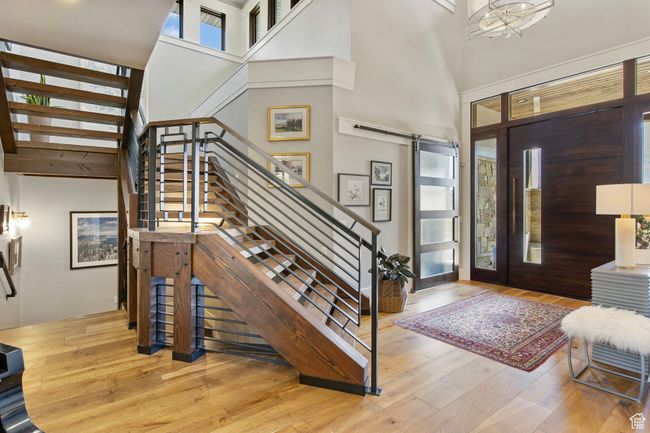 Entrance foyer featuring wood finished floors, a barn door, a towering ceiling, and stairs | Image 11