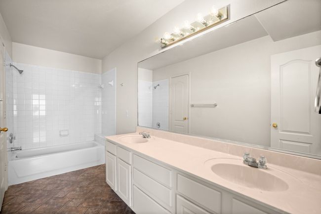 Bathroom featuring double vanity, stone finish flooring, and washtub / shower combination | Image 11