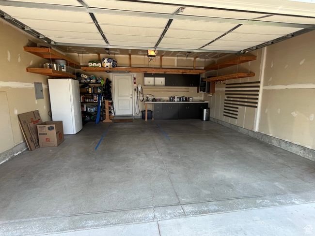 Garage with a garage door opener, electric panel, and freestanding refrigerator | Image 28