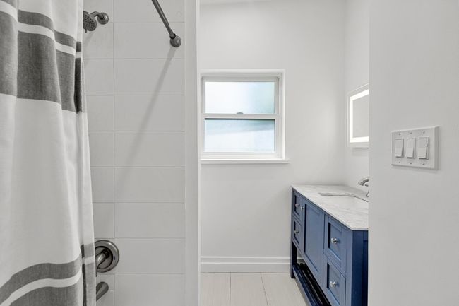 Bathroom with tile patterned floors, baseboards, a shower with shower curtain, and vanity | Image 21