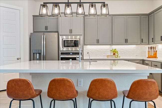 Kitchen with gray cabinets, light countertops, backsplash, and stainless steel appliances | Image 11