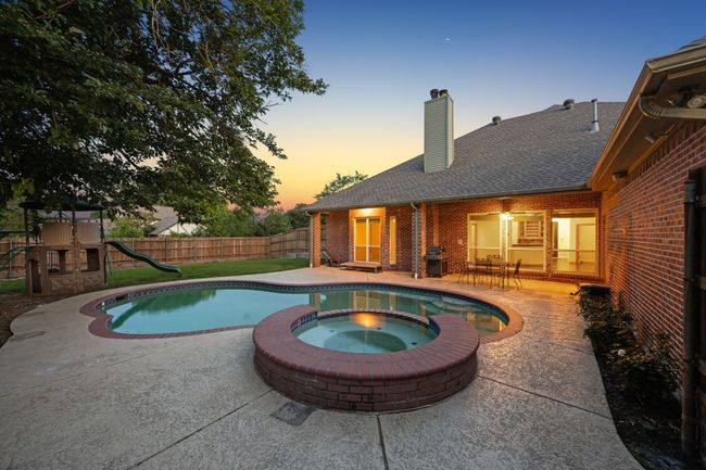 Pool at dusk featuring a patio, a pool with connected hot tub, and a playground | Image 32