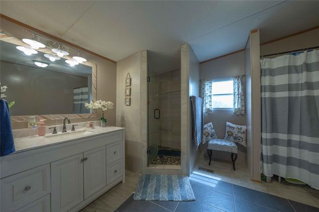 Bathroom with tiled shower, tile floors, crown molding, vanity, and lofted ceiling | Image 18