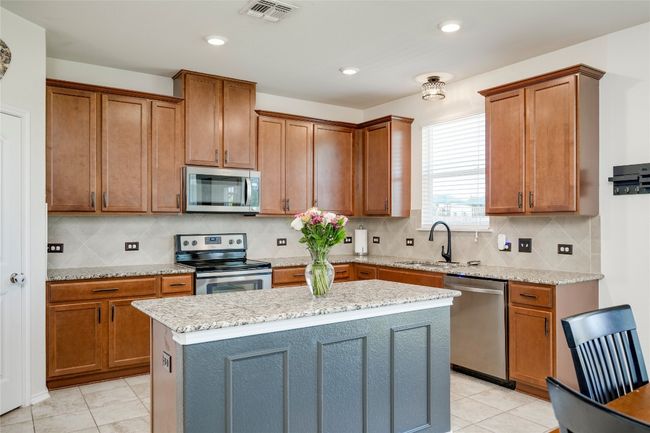 Kitchen with appliances with stainless steel finishes, light tile patterned flooring, tasteful backsplash, brown cabinetry, and recessed lighting | Image 8