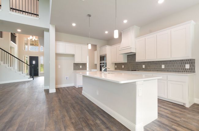 Kitchen featuring premium range hood, a sink, built in microwave, a center island with sink, and backsplash | Image 10