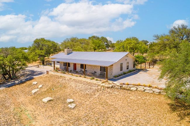 Ranch-style home featuring a chimney, metal roof, stone siding, a standing seam roof, and covered porch | Image 13