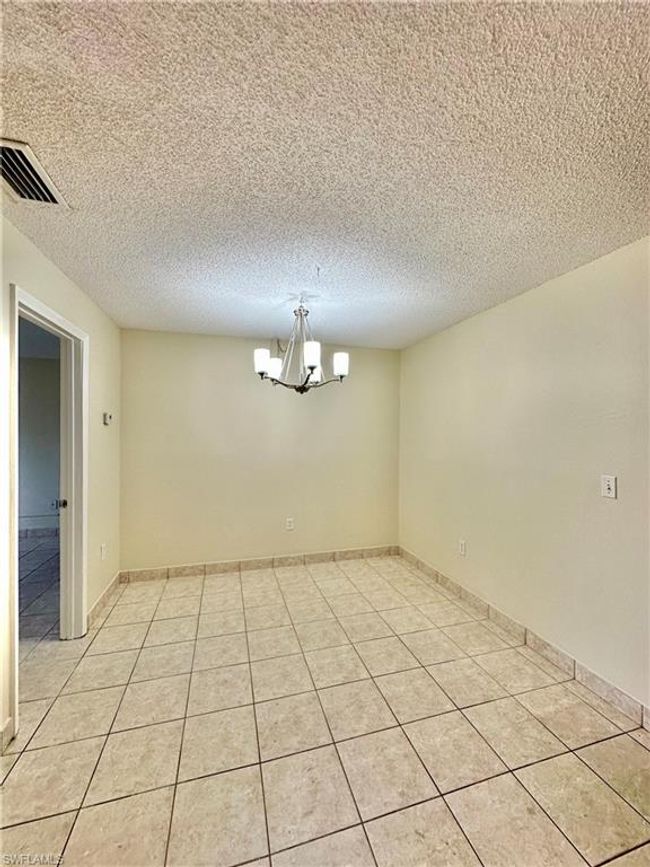 Spare room featuring a chandelier, light tile patterned floors, and a textured ceiling | Image 6