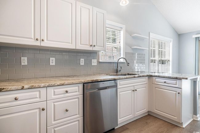 Kitchen featuring vaulted ceiling, dishwasher, decorative backsplash, and white cabinetry | Image 15