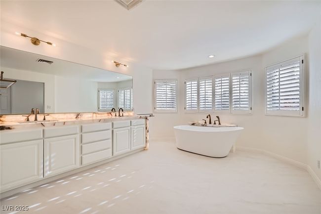 Full bathroom with double vanity, visible vents, a sink, a freestanding tub, and baseboards | Image 38