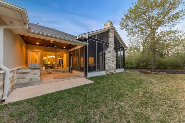 Rear view of property with ceiling fan, a chimney, area for grilling, a sunroom, and a lawn | Image 32