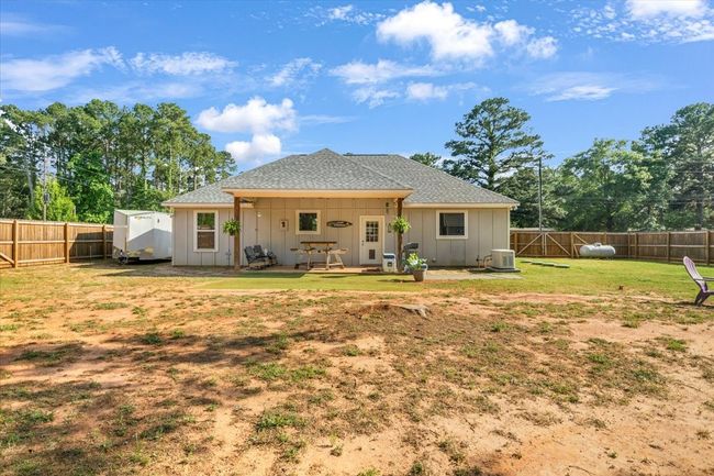 Rear view of property with a yard, a fenced backyard, central AC, and board and batten siding | Image 32