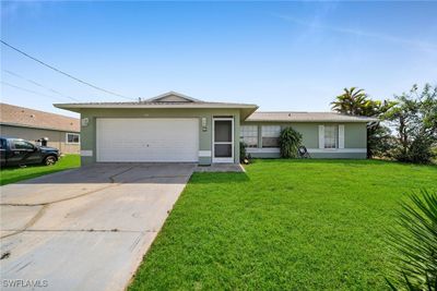 Ranch-style home featuring a front yard and a garage | Image 1