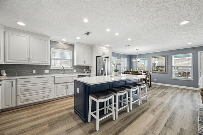 Enjoy a modern kitchen, updated in 2020, featuring quartz countertops, a farmhouse sink, soft-close cabinetry, and a reverse osmosis water system, seamlessly connected to the dining area. | Image 6