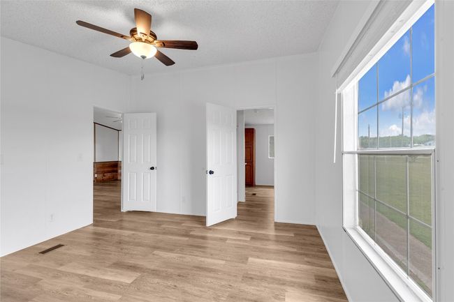 Empty room featuring ceiling fan, light wood-style floors, and a textured ceiling | Image 26
