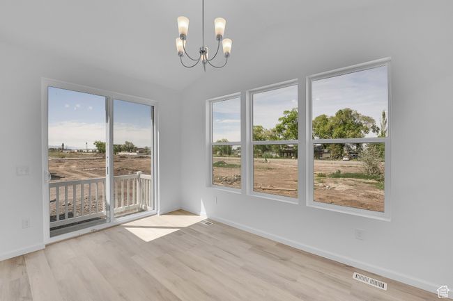 Unfurnished room featuring wood finished floors, a chandelier, and lofted ceiling | Image 10