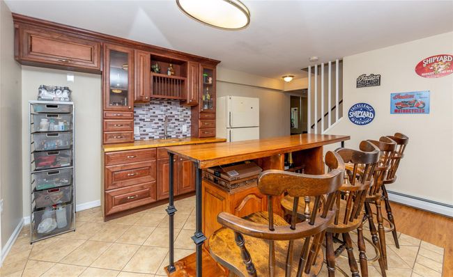 Kitchen with freestanding refrigerator, decorative backsplash, a baseboard heating unit, glass insert cabinets, and light tile patterned floors | Image 41