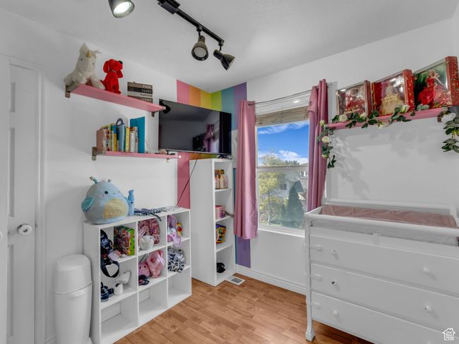 Bedroom with light wood finished floors, track lighting, and baseboards | Image 28