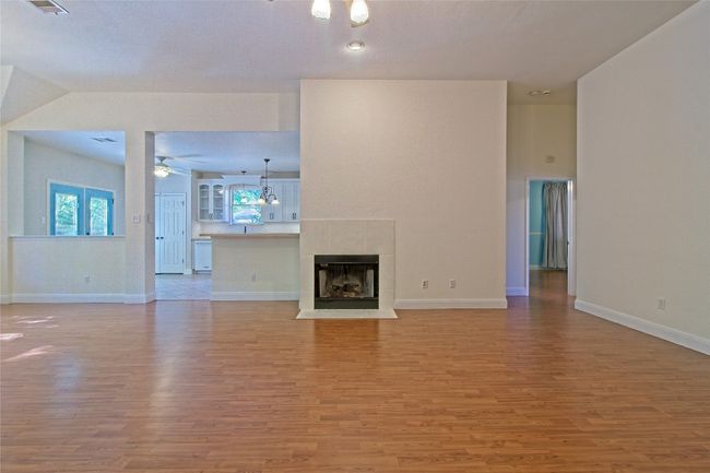 Unfurnished living room with light wood-style floors, a ceiling fan, and a tiled fireplace | Image 9