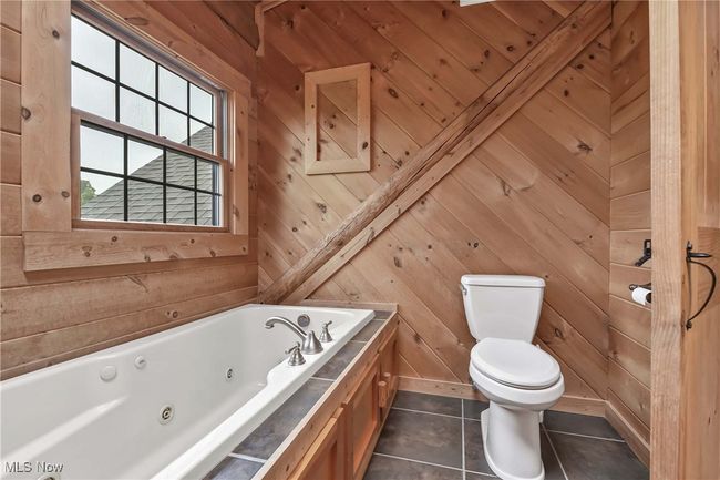 View of soaker tub window overlooking back yard, toilet and tile floor in primary bathroom | Image 27