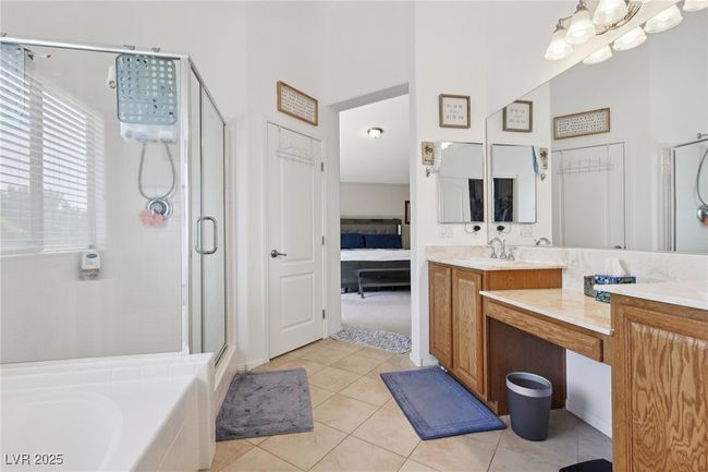 Full bath featuring a stall shower, vanity, tile patterned flooring, a towering ceiling, and a bath | Image 53