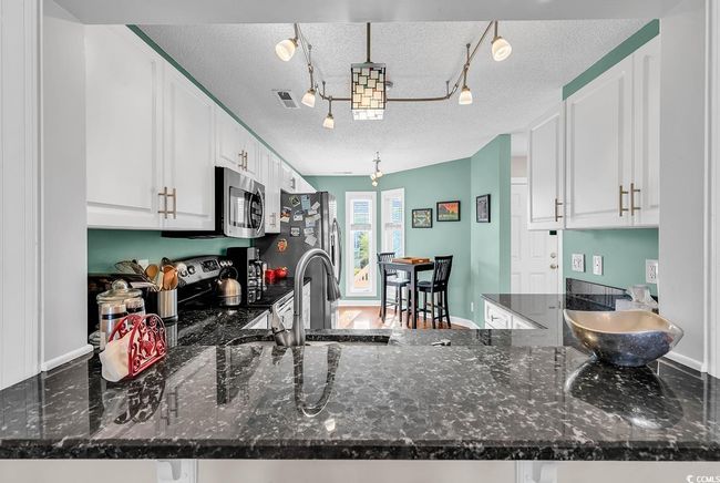 Kitchen featuring track lighting, a textured ceiling, and appliances with stainless steel finishes | Image 5
