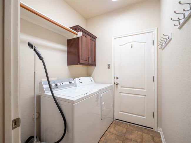 Laundry area with cabinet space, independent washer and dryer, and stone finish flooring | Image 18