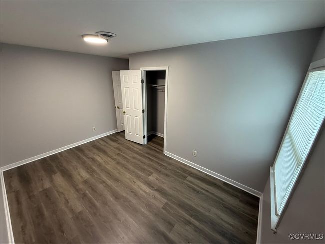 Unfurnished bedroom with dark wood-type flooring, baseboards, and a closet | Image 5