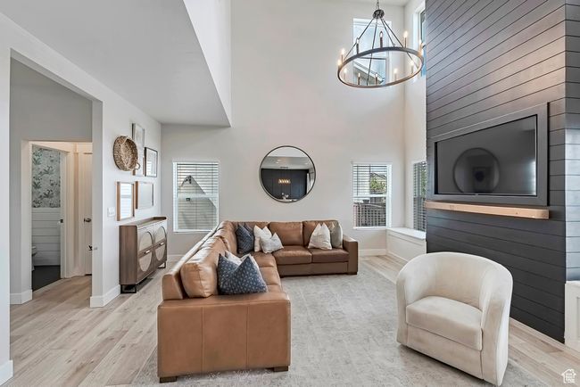 Living area with light wood-type flooring, a chandelier, baseboards, and a towering ceiling | Image 5
