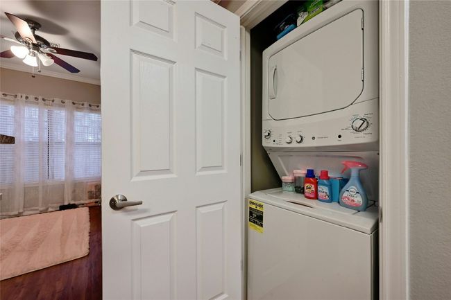Clothes washing area featuring ceiling fan, ornamental molding, stacked washer and clothes dryer, and dark wood-type flooring | Image 11