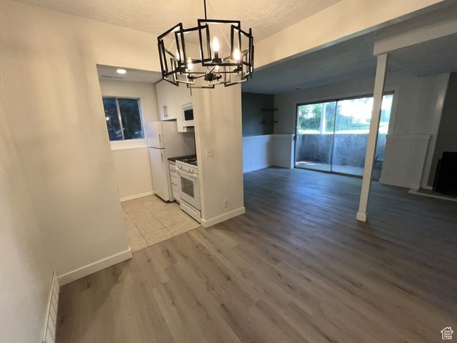 Unfurnished dining area featuring a chandelier, wood finished floors, baseboards, and a textured ceiling | Image 4