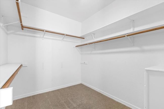 The primary suite's walk-in closet offers plenty of room for you and your partner's clothing needs. | Image 18