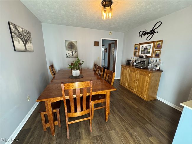 Dining area featuring dark wood-style flooring and a textured ceiling | Image 13