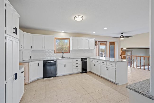 Kitchen featuring a sink, a peninsula, a healthy amount of sunlight, and black dishwasher | Image 30