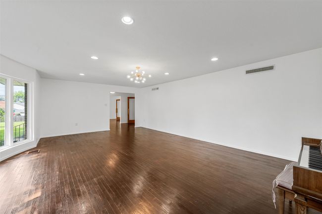 Unfurnished living room featuring dark wood-style floors, a chandelier, recessed lighting, and baseboards | Image 6