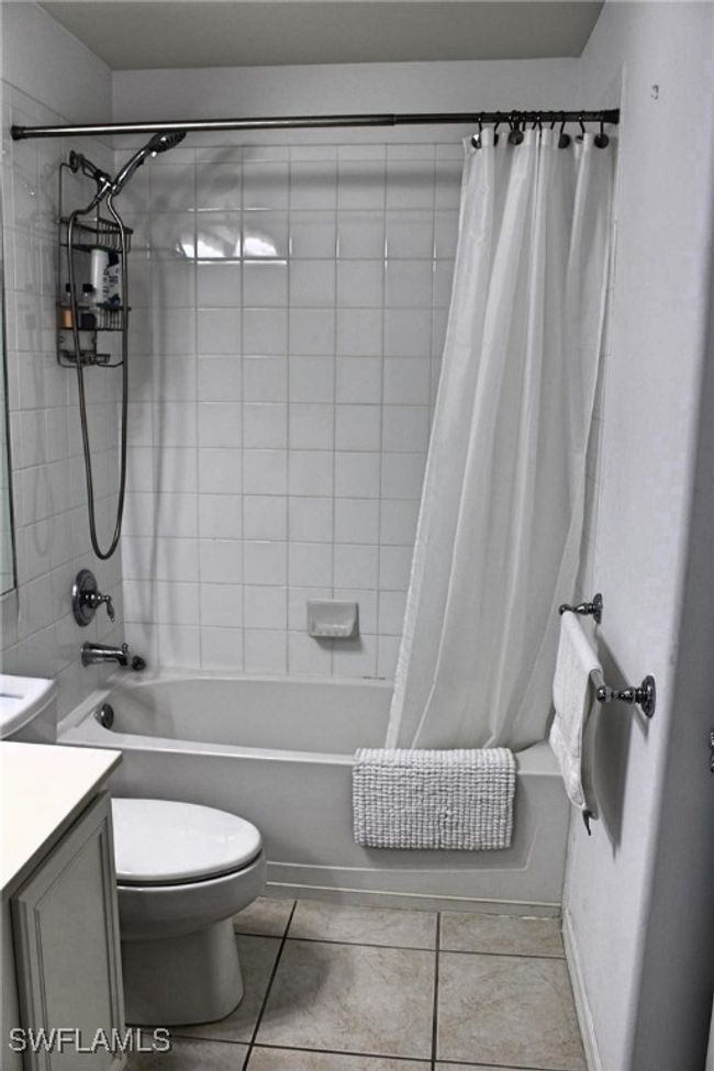 Bathroom featuring toilet, tile patterned floors, shower / bath combo with shower curtain, and vanity | Image 23