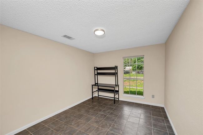 Charming third bedroom with natural light, versatile tile flooring, and serene views—perfect for a cozy retreat or home office. | Image 28