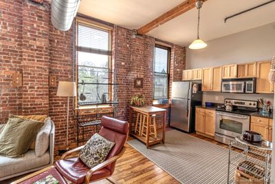 Note the open layout, 10 foot ceilings, exposed brick/air ducts, and the original hardwood flooring in this fabulous living room! | Image 2