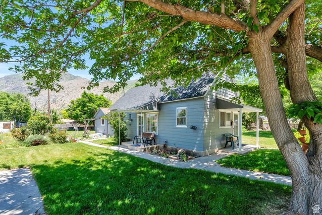 View of side of home featuring a mountain view, a yard, a patio area, and roof with shingles | Image 20
