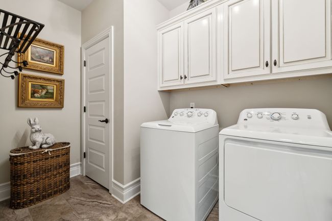 Spacious Laundry room with cabinet storage and water heater closet. Tile floors and hanging clothing rack. | Image 31