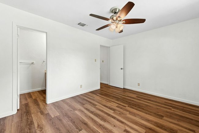 Unfurnished bedroom featuring wood finished floors, a ceiling fan, and a walk in closet | Image 12